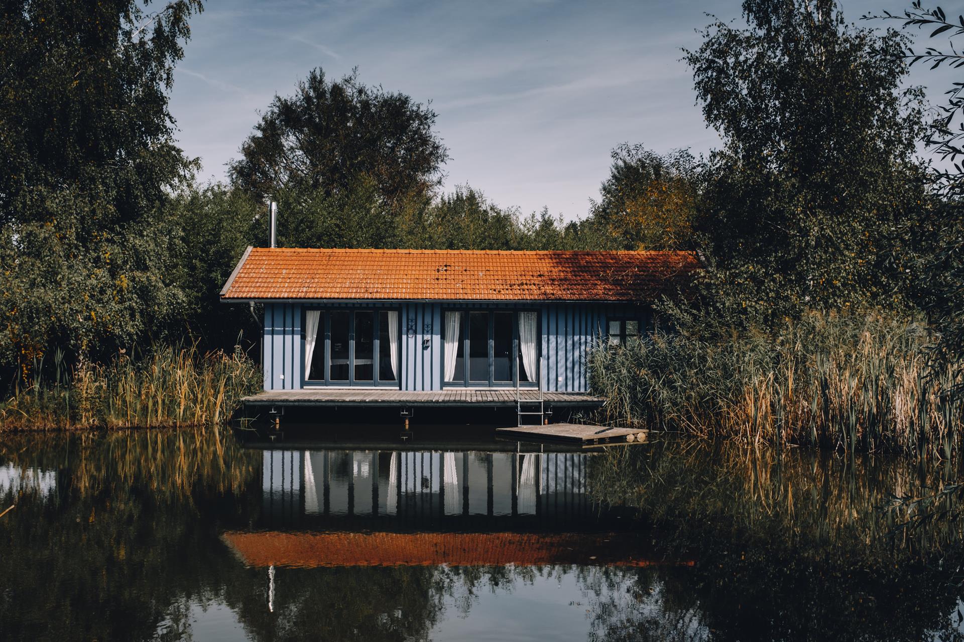 Share for Real_Bootshaus in Blau mit Bootssteg und Teich